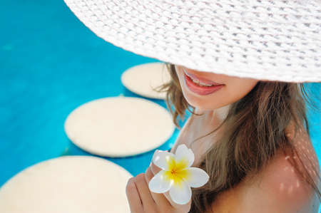 Beautiful woman in a white hat with a flower close-upの写真素材