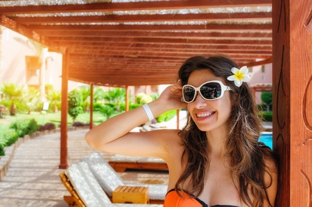beautiful young woman sitting on a lounger by the pool.の写真素材