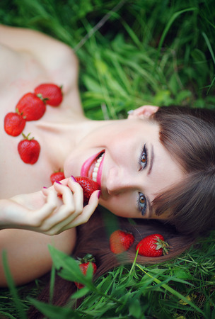 portrait of a beautiful woman eating strawberries in the park.の写真素材