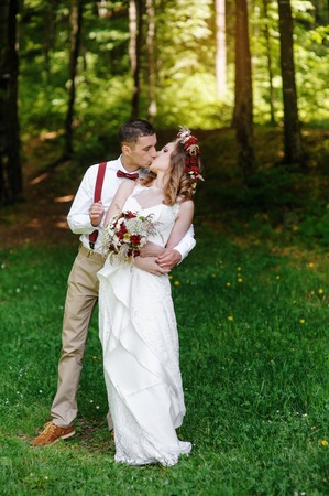 happy bride and groom walking in the summer forest.の写真素材