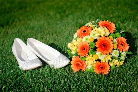 Bridal bouquet and white shoes bride lying on the grass.の写真素材