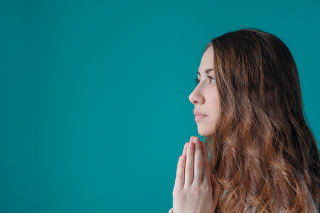 young woman praying with her hands folded.