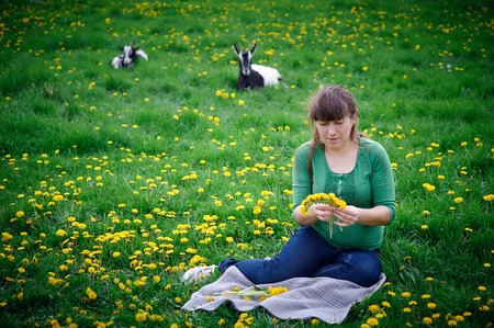 Pregnant woman weaves a wreath in the meadowの写真素材