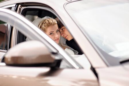 bride and groom kissing in wedding car.