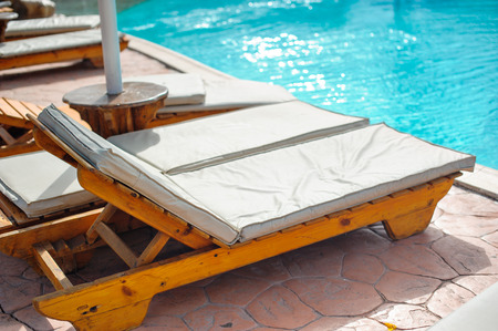 Wooden bed beside the pool. The beds are arranged behind the pool's edge.