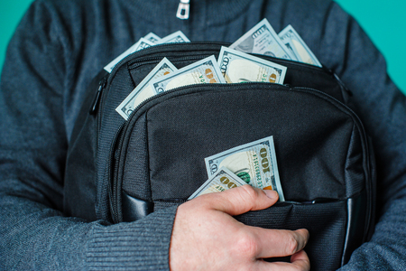 man holding a black briefcase with dollars.の写真素材