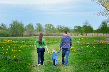 Happy young family walking down the road outside in green nature.の写真素材