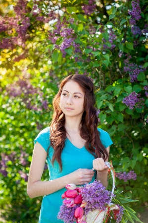 Beautiful woman in the spring garden with a basket of flowers.