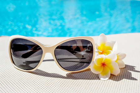 sunglasses and plumeria flowers near the pool.の写真素材