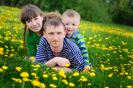 Happy young boy on meadow with his parents.の写真素材