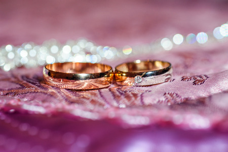 Two gold wedding rings lie on a pillow close upの写真素材