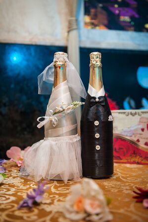 Two bottles of champagne decorated as a bride and groom standing on table.の写真素材