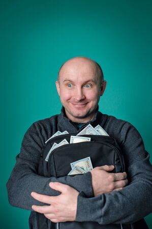 excited businessman holding bag with money and smiling.