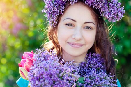 Beautiful girl with a bouquet of lilac in the hands in the spring park.の写真素材