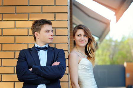 The bride and groom stand on the corner of a brick building.の写真素材