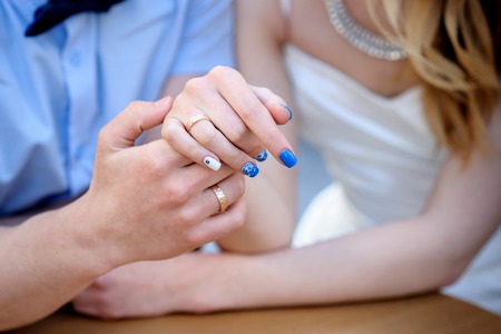 Portrait of smiling bride and groom sitting at cafe and holding handsの写真素材