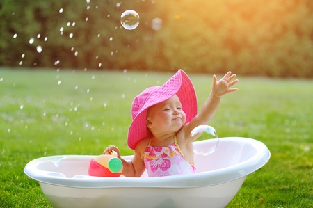 little girl bathes in a bath with soap bubbles.の写真素材