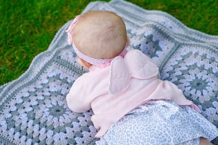 Happy little girl lying on a blanket in the park.