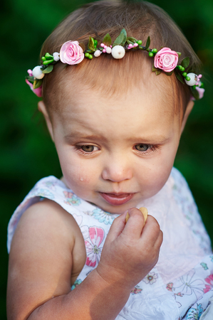 beautiful smiling little girl with a wreath on her head close-upの写真素材