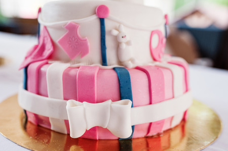 Beautiful pink birthday cake with pillow on table.