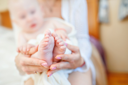 Hands of mother holding baby legs close up.の写真素材