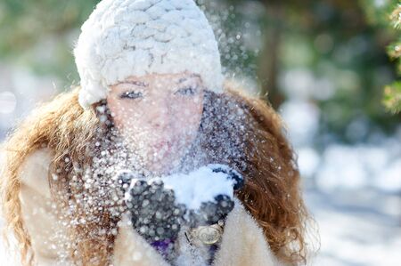 beautiful woman in winter blows snow with hands.の写真素材