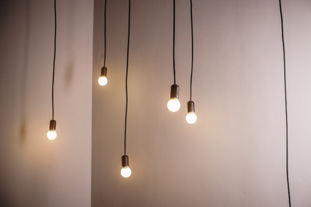 many lamps on a long cord and hanging light in the room.