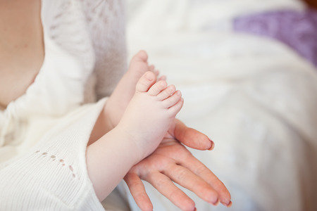 Happy young mother holding little feet of her son.の写真素材