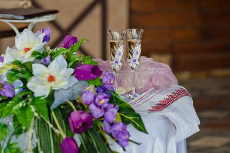 Two wedding glasses and bridal bouquet on stone in summer gardenの写真素材