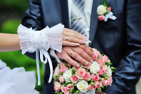 Hands and rings on wedding bouquetの写真素材