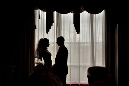 silhouette of a bride and groom on the background of a windowの写真素材