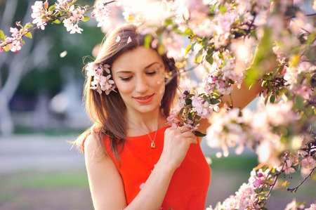 Beautiful young girl in the park and a flowering treeの写真素材