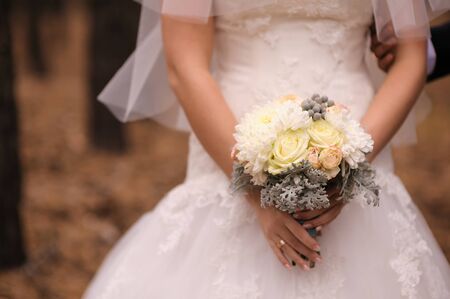 Bride holding white wedding bouquet of rosesの写真素材