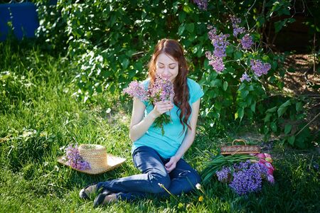 beautiful woman sitting on the grass in the spring park.の写真素材