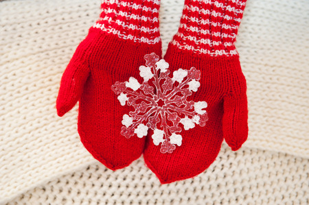 woman hand in red gloves holding white big snowflake.の写真素材