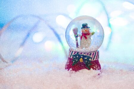 Snow globe with happy snowman blured background.の写真素材