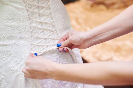 bridesmaid helps the bride dress.