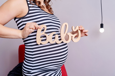 Pregnant belly with symbol text baby in her hands.の写真素材