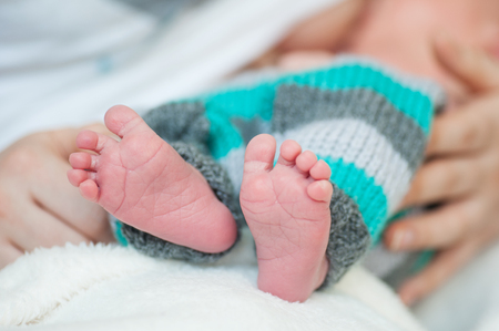 Infant's small feet closeup with mother hands.の写真素材