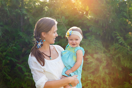 Mom keeps daughter in her arms and plays on the nature.の写真素材
