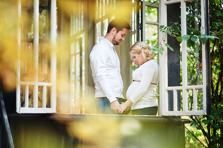 husband with his pregnant wife on the porch of the house.の写真素材