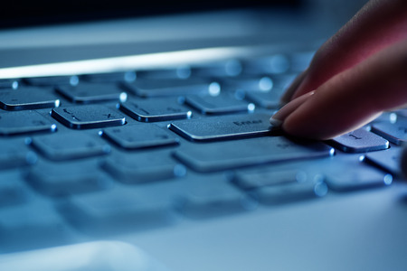 Woman's fingers on the laptop keyboard in the office close up