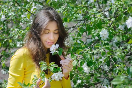 Beautiful woman smelling a flower in the spring garden.