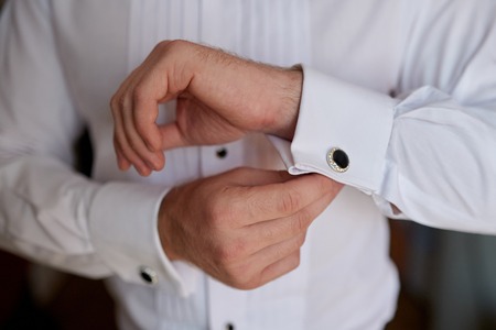 man in white shirt near window dress cufflinks.