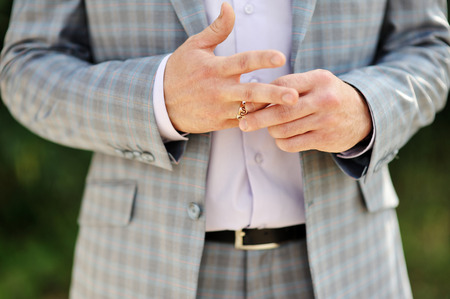 Groom wears a ring on his finger close upの写真素材