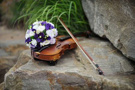 beautiful bridal bouquet and violin on the rock.の写真素材