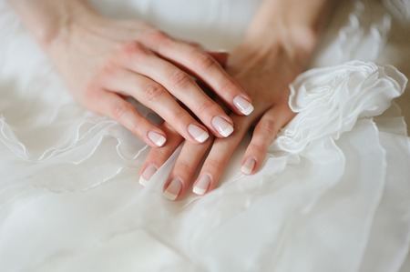 bride's hands with a manicure on her dress close-up
