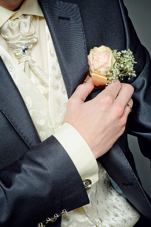 groom putting boutonniere on the gray suit in wedding day.の写真素材