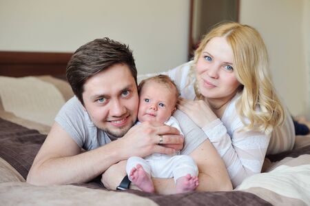 Happy Young Attractive Family parents with Newborn Baby in roomの写真素材