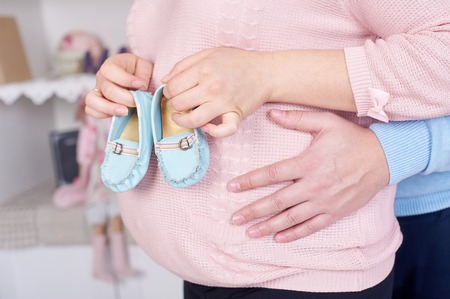 pregnant woman hugging her husband and they keep booties for unborn child.